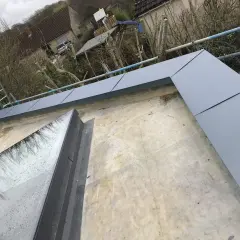 Nowa attyka z szarego metalu otacza dach z oknem dachowym.