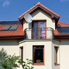 Nowoczesny dom z wykusza, balkonem i panelami słonecznymi na dachu.