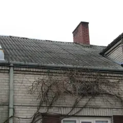 Dach pokryty eternitem, który zawiera azbest, z kominem i anteną satelitarną.
