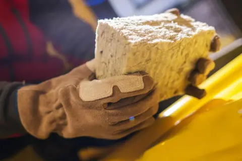 Rękawica trzyma blok wełny skalnej, materiału izolacyjnego.