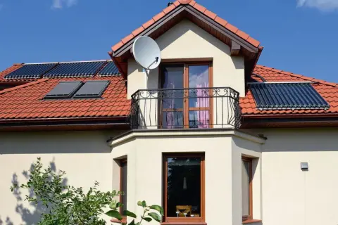 Nowoczesny dom z wykusza, balkonem i panelami słonecznymi na dachu.