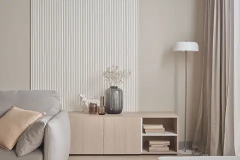 Nowoczesna ściana z ryflowaniem, komoda z książkami i wazonem, obok sofa. Idealne co na ścianę do salonu.