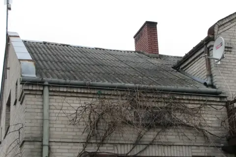 Dach pokryty eternitem, który zawiera azbest, z kominem i anteną satelitarną.
