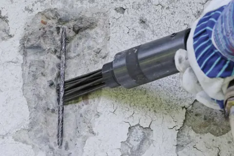 Narzędzie pneumatyczne przygotowuje beton do naprawy na zewnątrz.