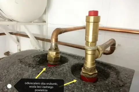 Dwa mosiężne śrubunki z miedzianymi rurkami, jeden z zaworem bezpieczeństwa. Woda leci, powietrza brak.