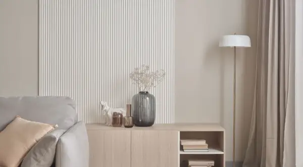 Nowoczesna ściana z ryflowaniem, komoda z książkami i wazonem, obok sofa. Idealne co na ścianę do salonu.