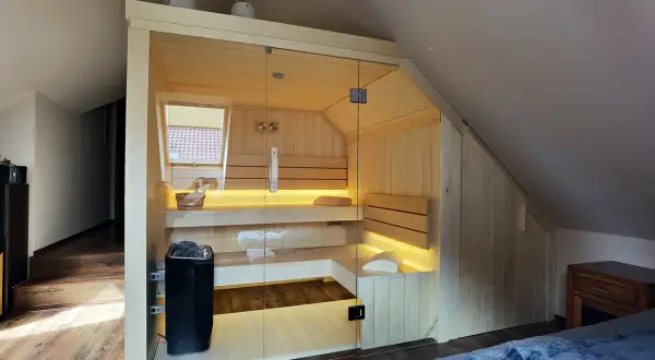 Nowoczesna sauna w domu, z przeszklonymi drzwiami i nastrojowym oświetleniem, idealna do relaksu.