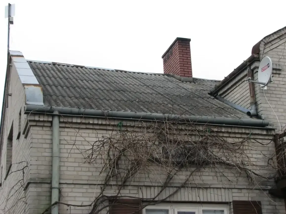 Dach pokryty eternitem, który zawiera azbest, z kominem i anteną satelitarną.